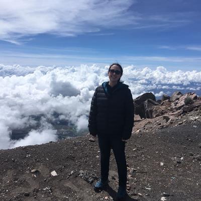 Eimear Gallagher is standing on a mountain top and she is above the clouds which can be seen in the background.